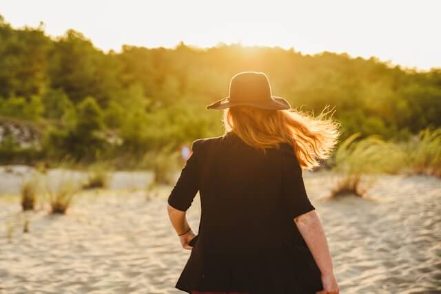 Kvinde på stranden - solbeskyttelse med skygge, hat og solcreme